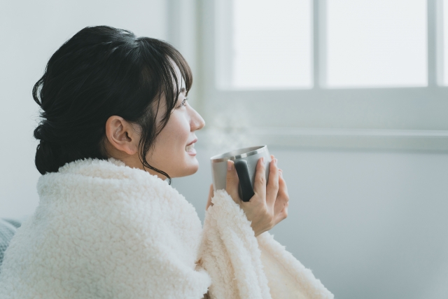 冬の寒い日にホットドリンクを飲む女性